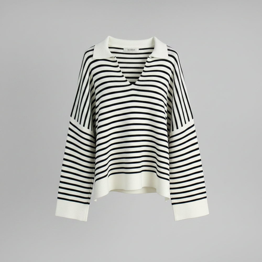 Black and white striped sweater on a hanger against a gray background