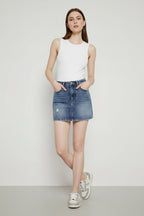Person wearing a blue denim skirt on a plain background