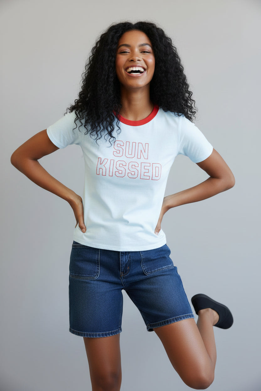 Woman wearing a 'Sun Kissed' t-shirt against a black and white striped background