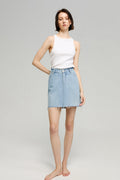 Woman wearing a white sleeveless top and light blue denim skirt on a gray background