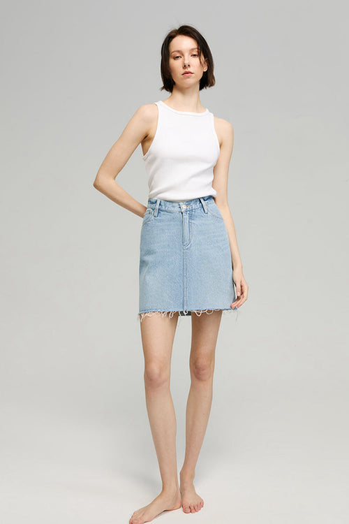 Woman wearing a white sleeveless top and light blue denim skirt on a gray background