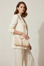 A beige, solid pattern, portable cosmetic bag with a metallic ring handle and a tassel.
