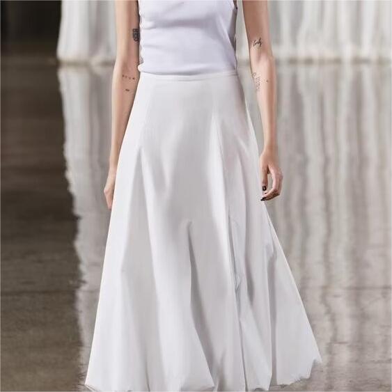 Person wearing a white skirt and white top against a neutral background