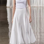Person wearing a white skirt and white top against a neutral background