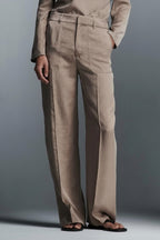 A model wearing a beige straight-leg pant suit with a collared blazer.