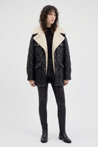 Person wearing a black quilted jacket on a white background