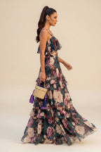 Woman in a floral dress standing outdoors with palm trees and garden in the background