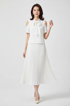 White blouse with a bow and pleated white skirt on a white background