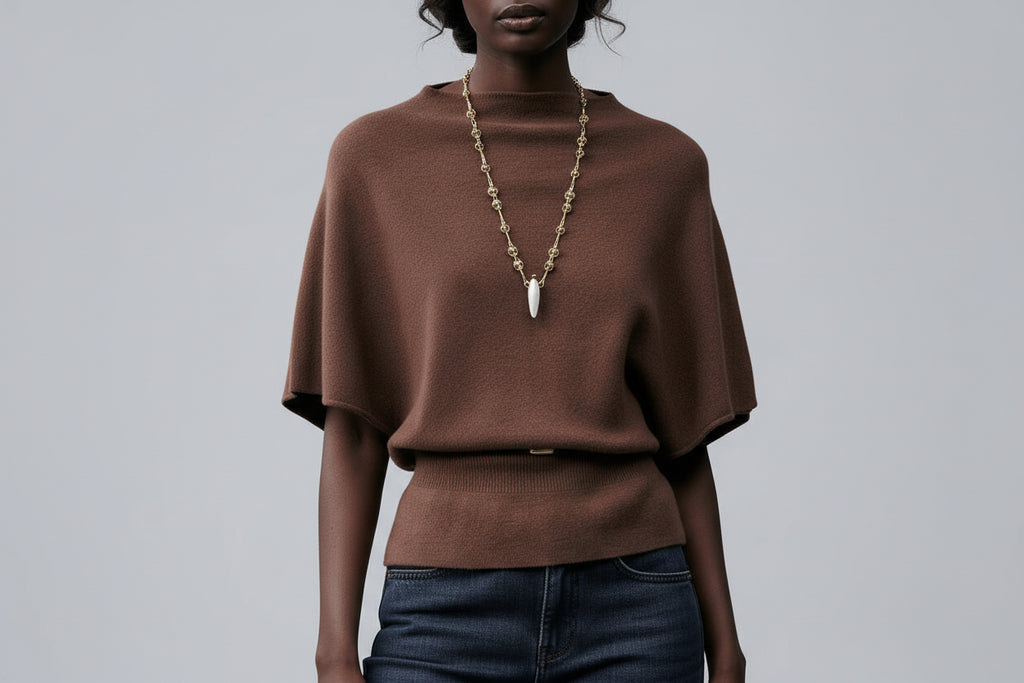 Woman wearing a brown sweater and dark blue jeans on a gray background