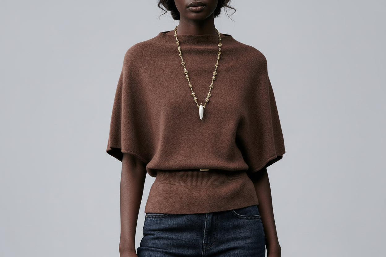Woman wearing a brown sweater and dark blue jeans on a gray background