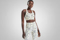 Woman wearing a patterned sports bra and leggings on a beige background
