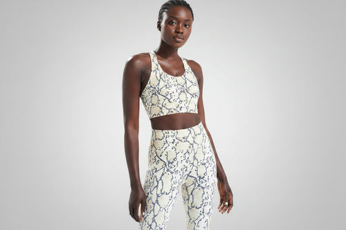 Woman wearing a patterned sports bra and leggings on a beige background