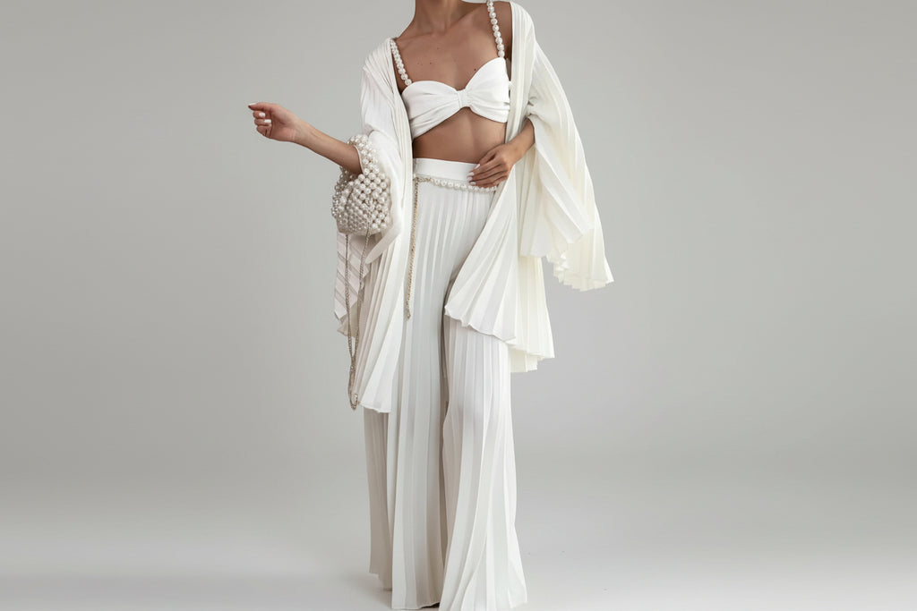 Person wearing a white outfit with a matching shawl in a room.