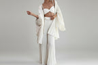 Person wearing a white outfit with a matching shawl in a room.