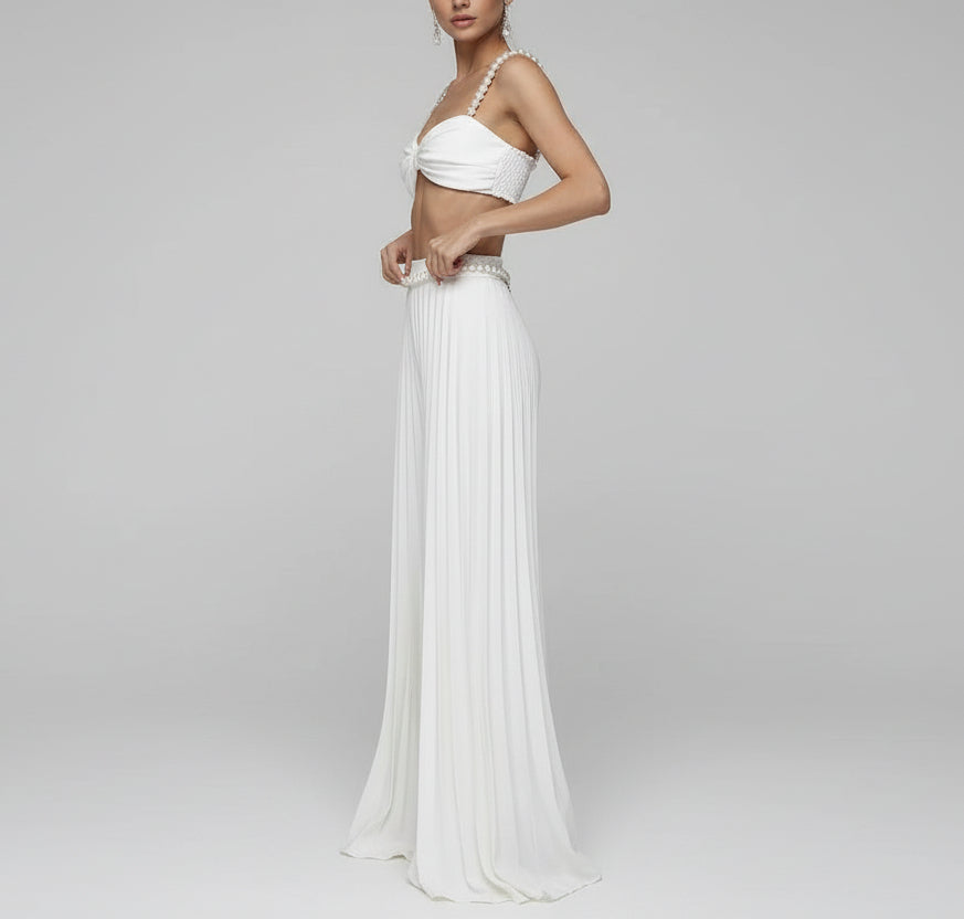 Woman wearing a white outfit with a pleated skirt in front of a mirror.