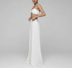 Woman wearing a white outfit with a pleated skirt in front of a mirror.