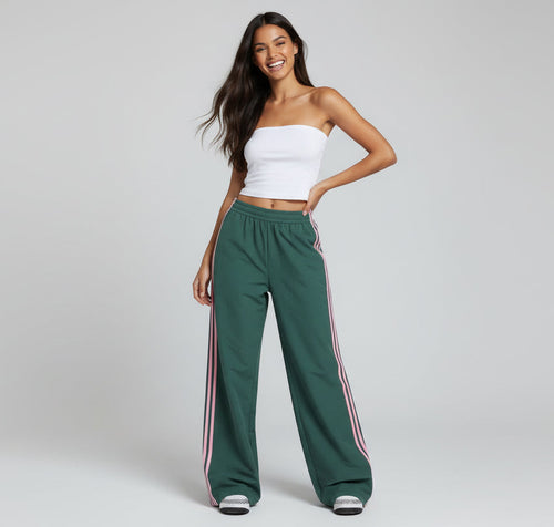 Woman wearing a white strapless top and green pants with pink stripes on a gray background