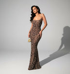 Woman in a leopard print dress standing in a room with a white couch and abstract painting.