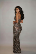 Woman in a leopard print dress standing in a hotel hallway.