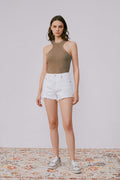 Woman wearing a brown halter top and white shorts on a plain background