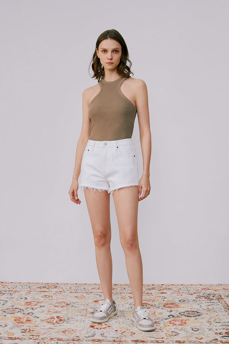 Woman wearing a brown halter top and white shorts on a plain background