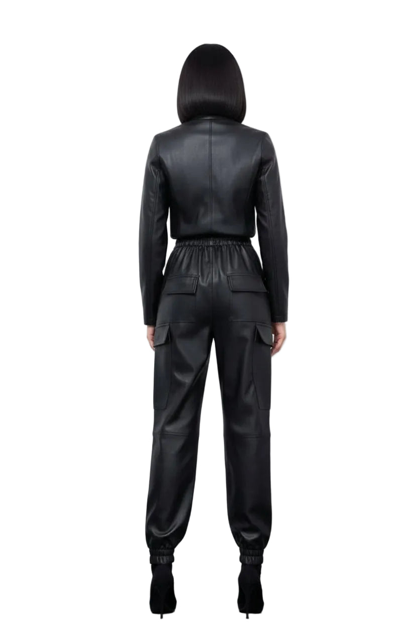 Person wearing a black leather jumpsuit against a white curtain background