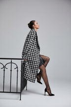 Person wearing a houndstooth patterned outfit with fishnet stockings on a city street.