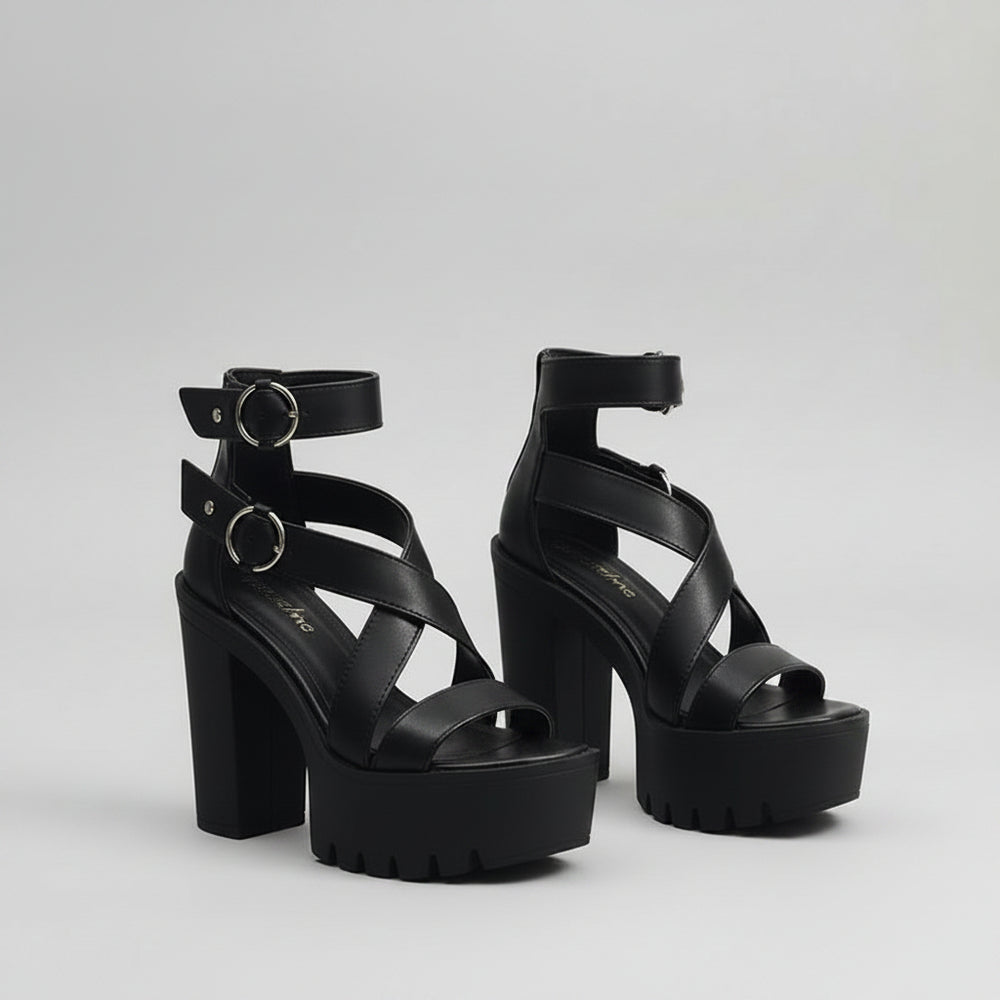 Person wearing black platform sandals on a tiled floor.