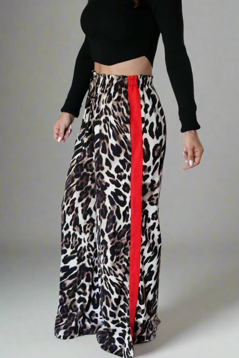 Person wearing a black top and leopard print skirt with a red stripe indoors.