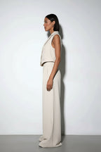 Person wearing a beige sleeveless top and wide-leg pants against a white background