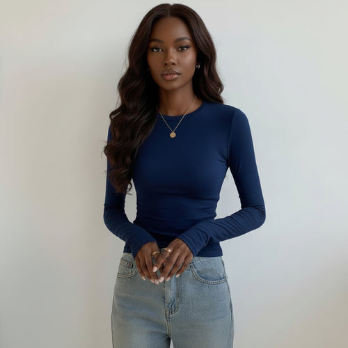 Person wearing a blue long-sleeve top holding a coffee cup indoors.