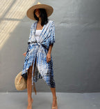 Woman wearing a blue and white patterned kimono-style garment against a gray wall.