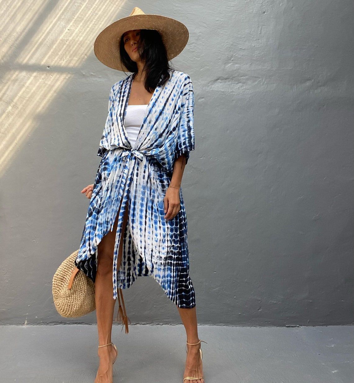 Woman wearing a blue and white patterned kimono-style garment against a gray wall.