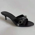 A black PU leather sandal with a round head and a decorative buckle, featuring a wine glass heel.