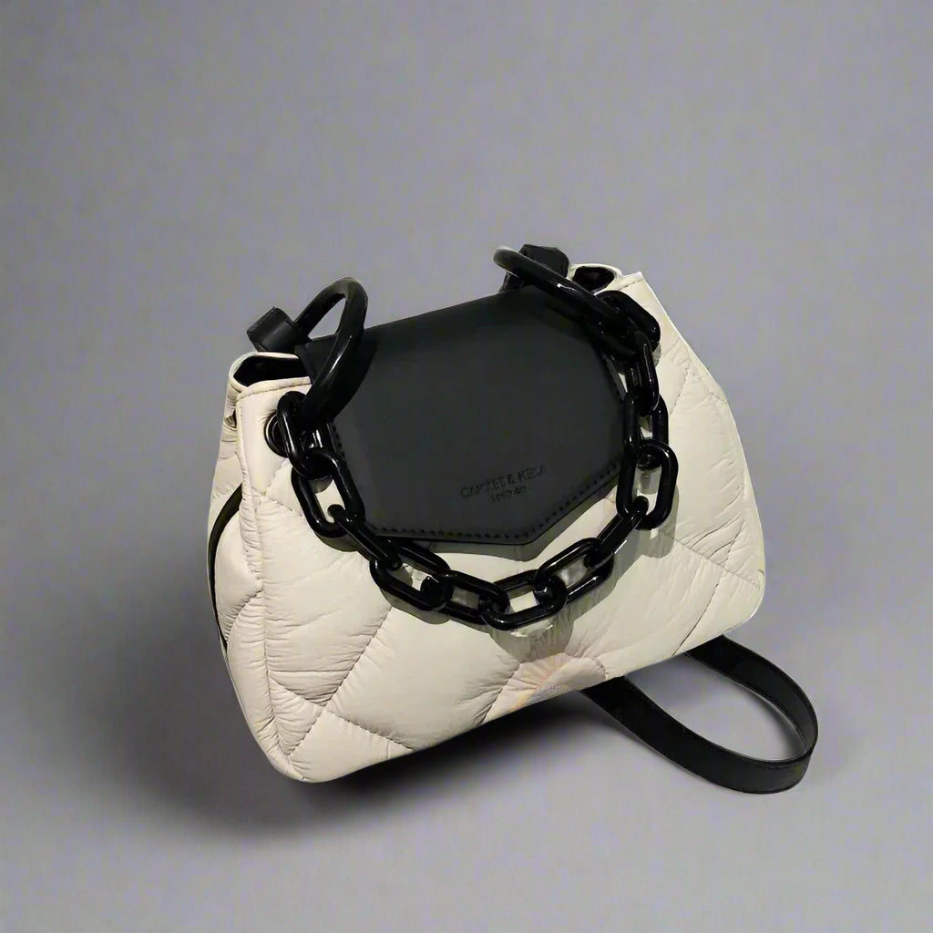 White quilted handbag with black chain detail on a gray background