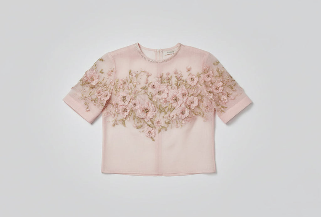 Pink blouse with floral embroidery on a blurred background
