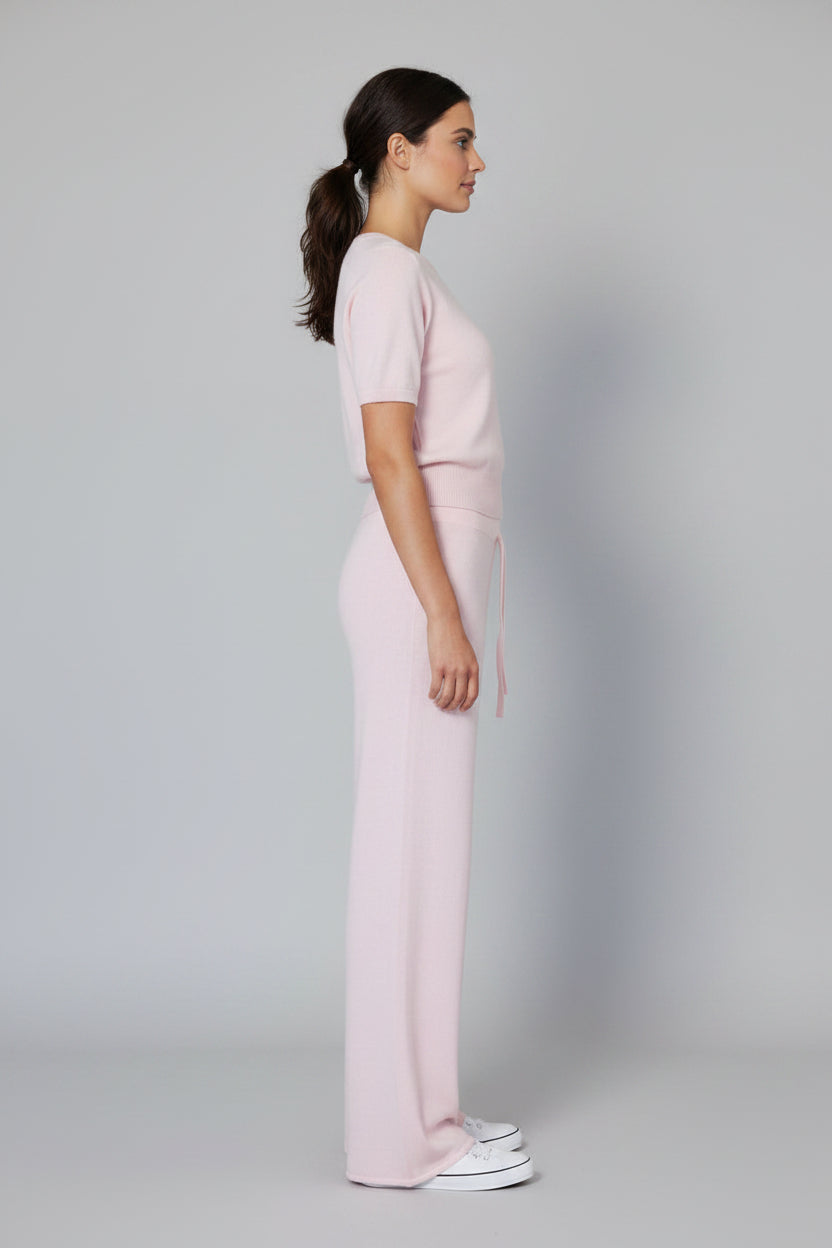 Person wearing light pink sweatpants on a plain background