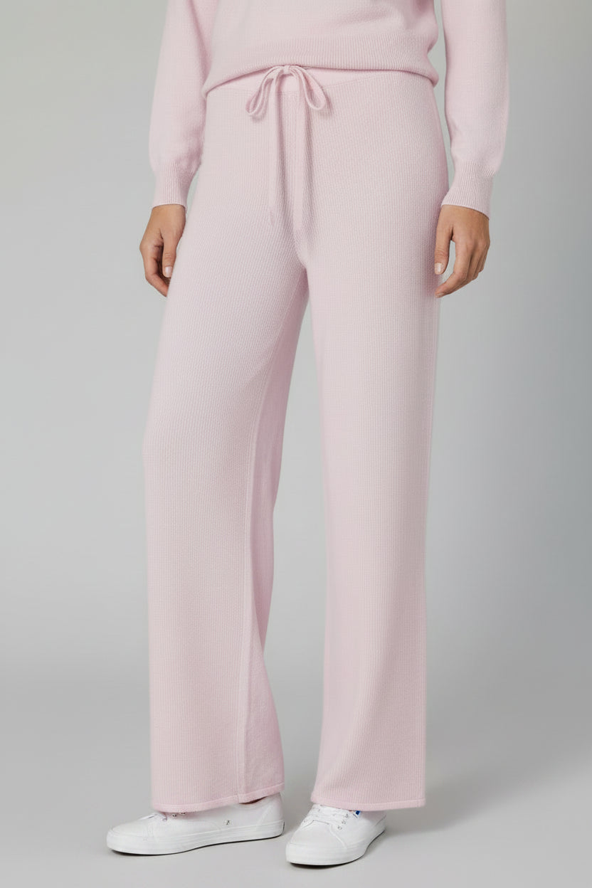 Person wearing light pink pants on a plain background