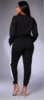 A three-panel studio photo of a woman modeling a matching color-block sweatshirt and jogger set. The left panel shows a navy, white, and red version; the center panel shows a black, white, and red version; the right panel shows the back view of the black set.