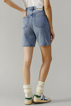 Person wearing blue denim shorts on a beige background