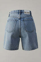 Blue denim shorts with a brand label on a beige background