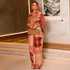 Woman in a long, flowing dress holding a gold clutch in an indoor setting.