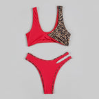 Red bikini with leopard print details on a light surface with sunglasses and a hat.