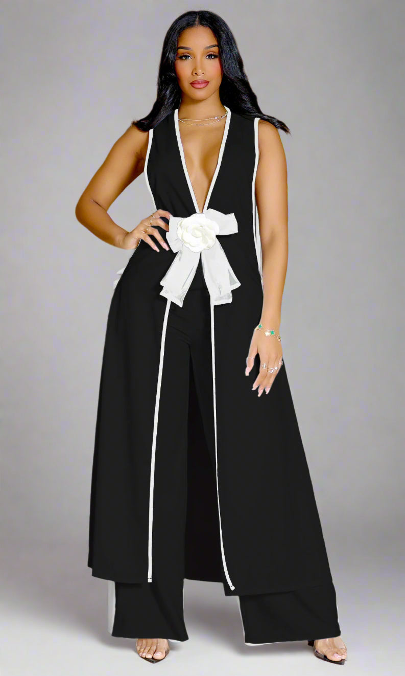 Woman wearing a black jumpsuit with a white bow tie on a gray background