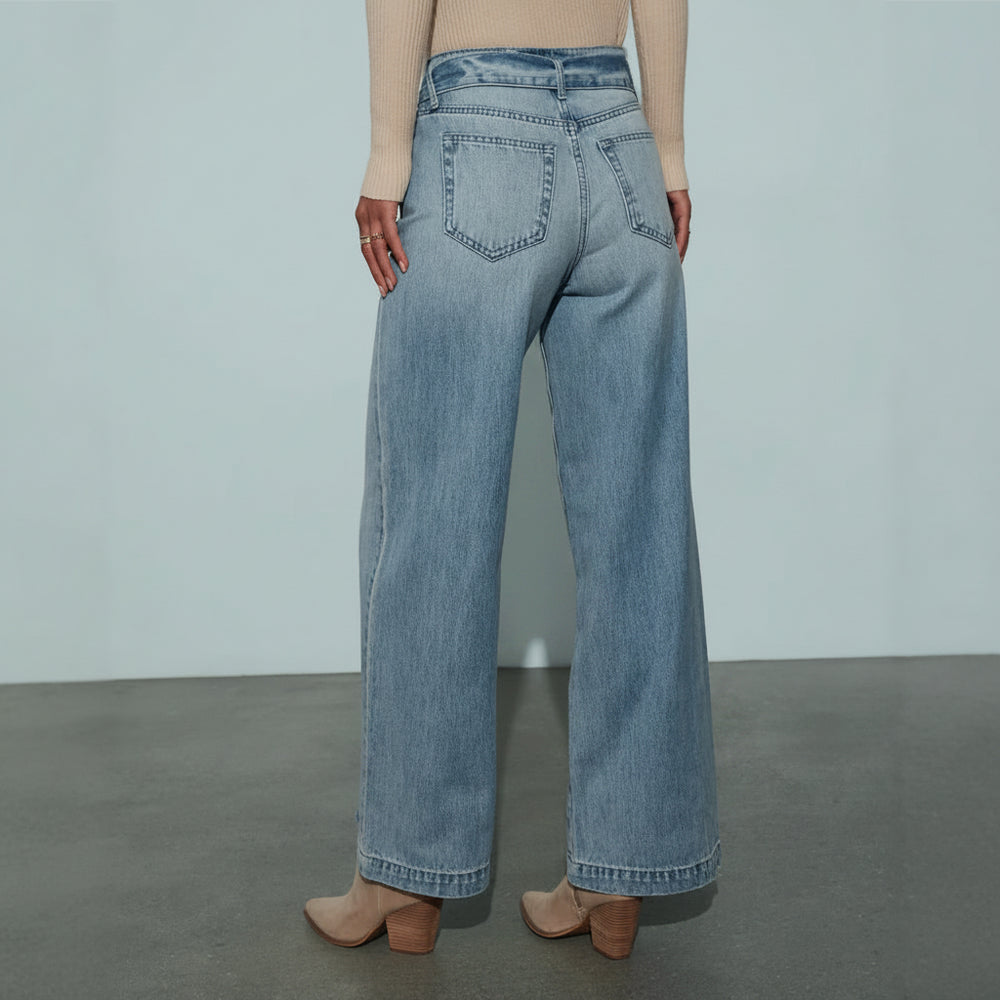 Person wearing light blue jeans on a plain background