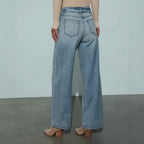 Person wearing light blue jeans on a plain background