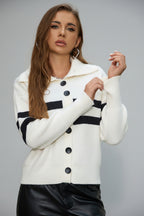 Woman wearing a white cardigan with black buttons and trim.