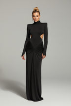 Woman wearing a black evening gown with cut-out design against a brown background
