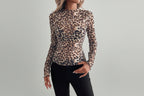 Person wearing a leopard print long-sleeve top in a room with white furniture and decor.