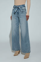 Person wearing light blue wide-leg jeans on a plain background